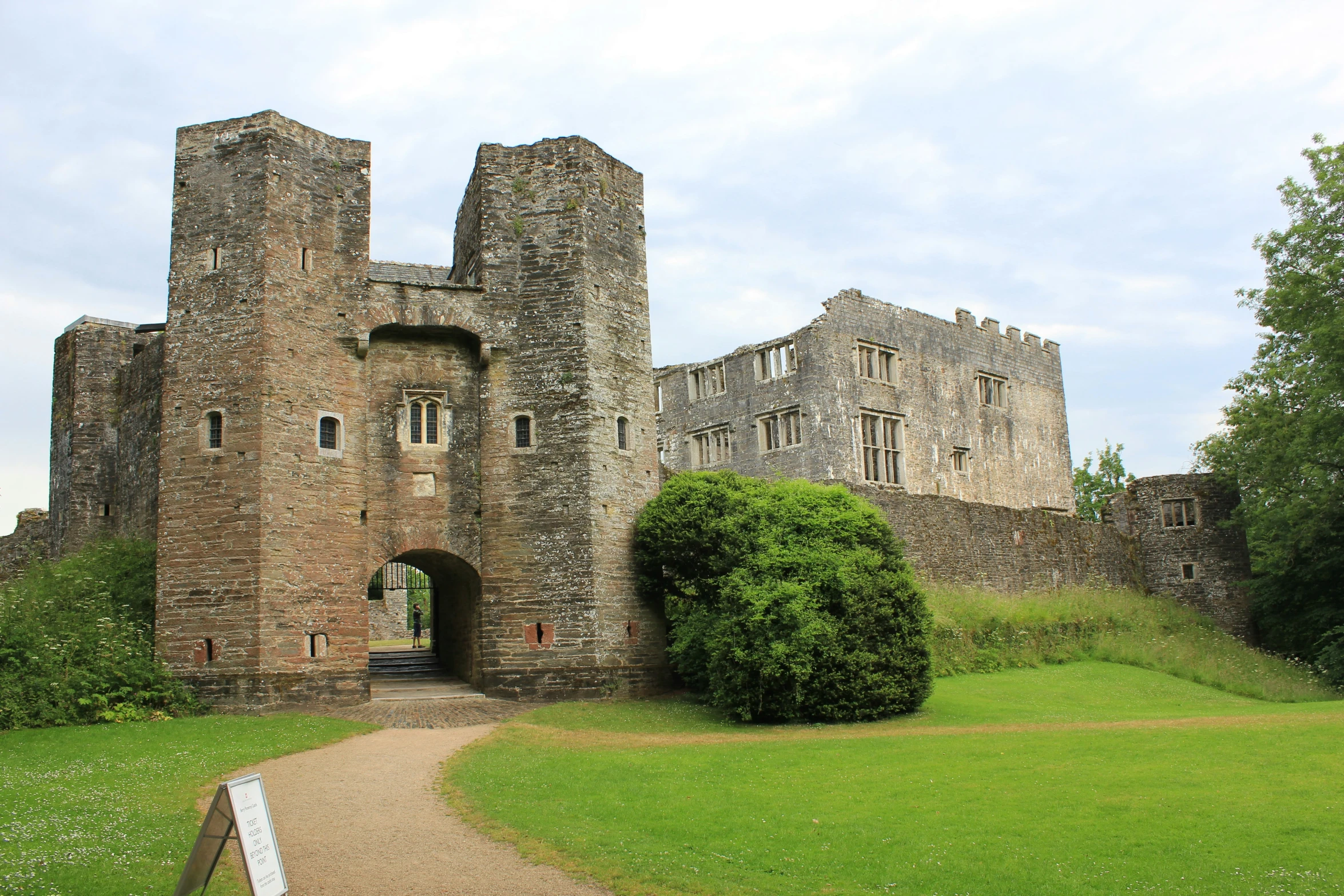 an old brick castle stands surrounded by lush green grass