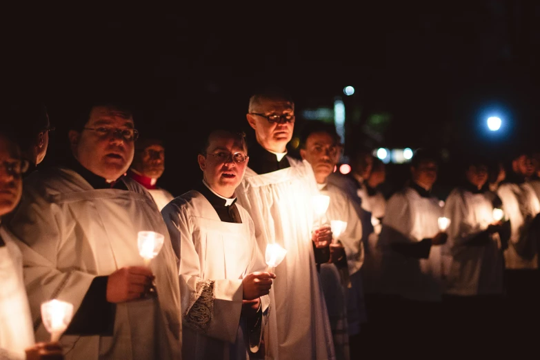 a large group of people are holding candles together