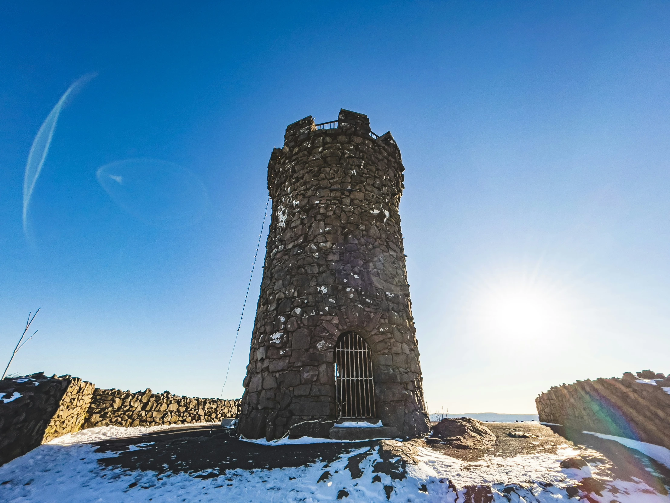 the sun shines on a tall tower sitting on top of a mountain