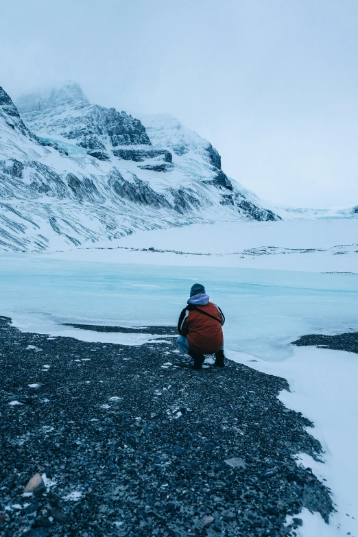 a man sitting on a rock next to a large body of water