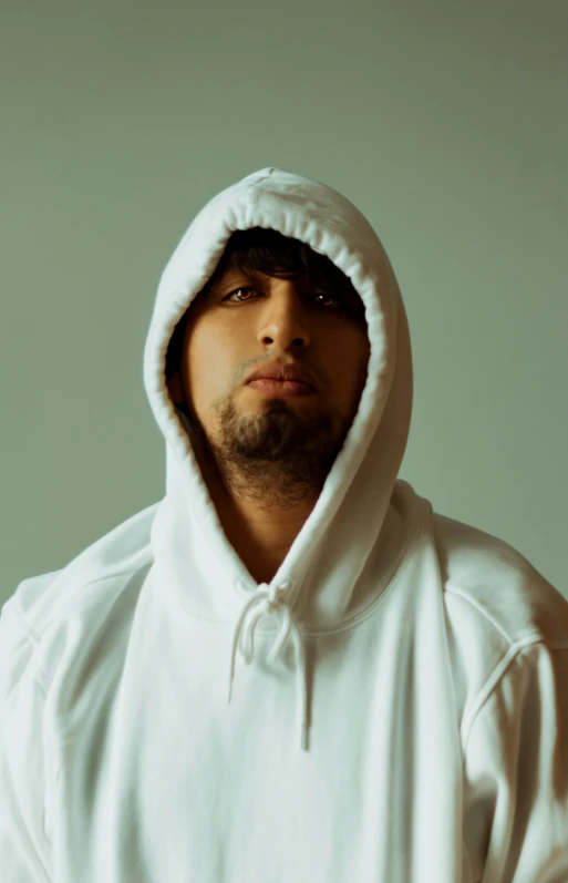 a man in a white hooded sweatshirt looks up