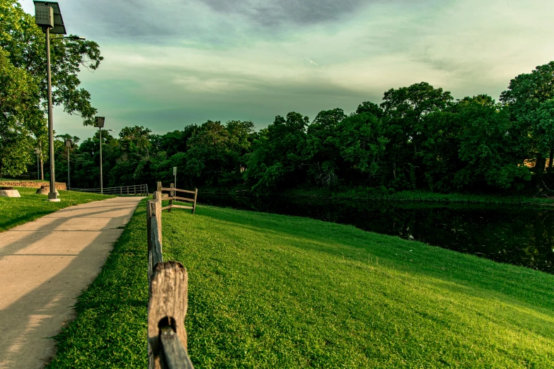 a small wooden bench in a grassy area next to a river