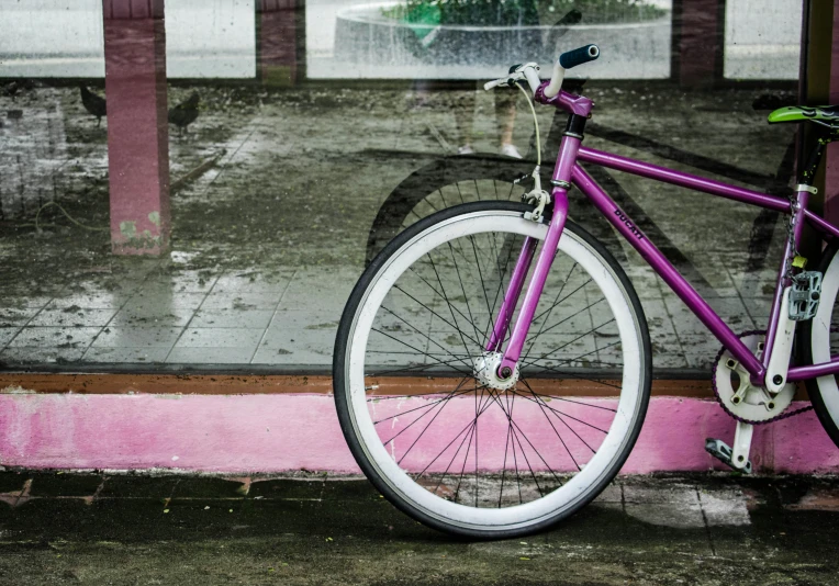 a purple bicycle is parked by a window