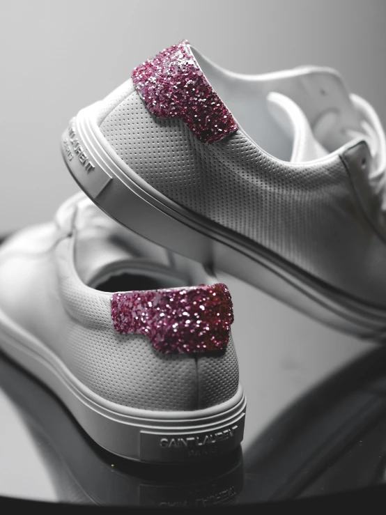 a pair of white shoes with glitter bow on them