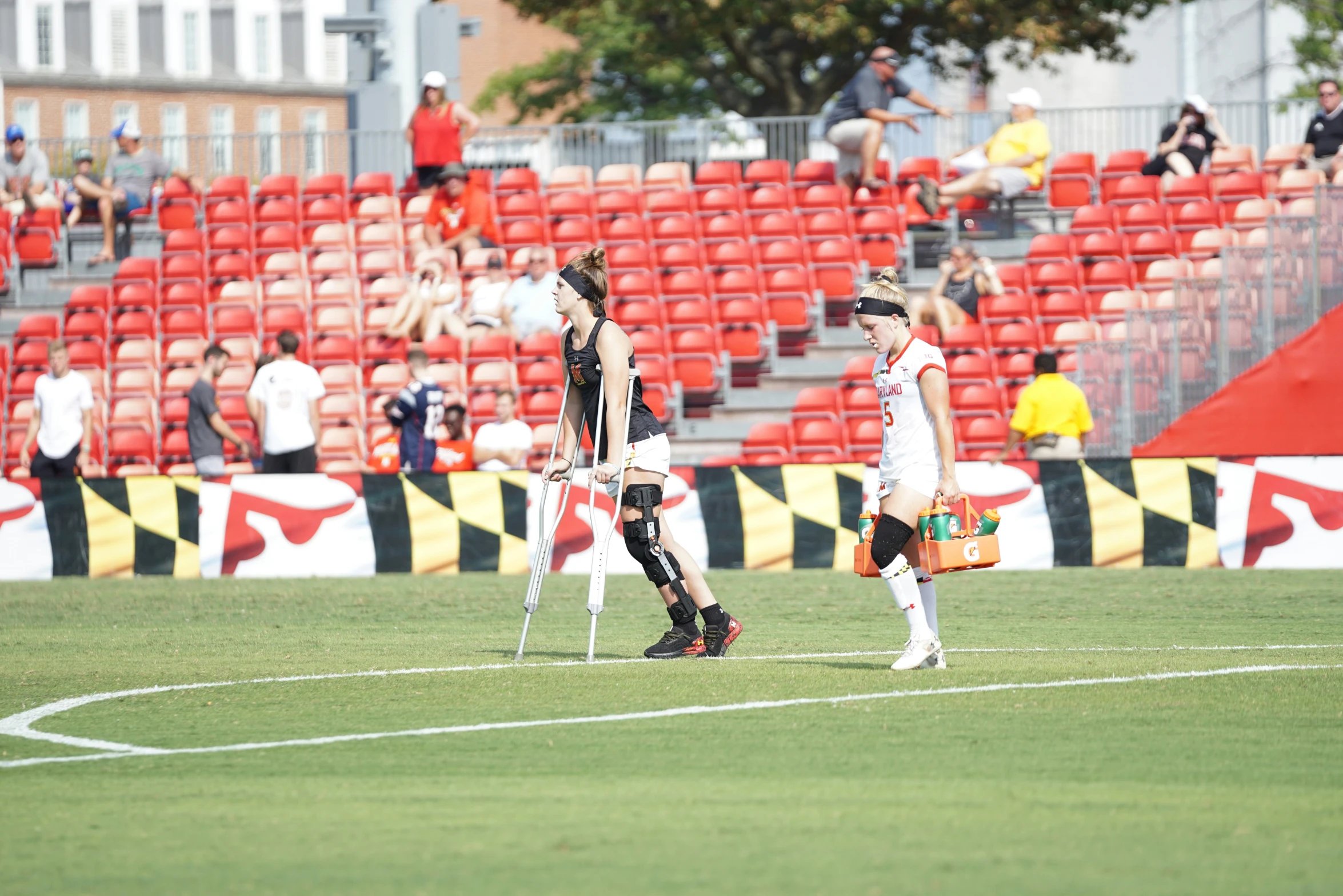 two soccer players in white uniforms standing on the field with their arms around each other