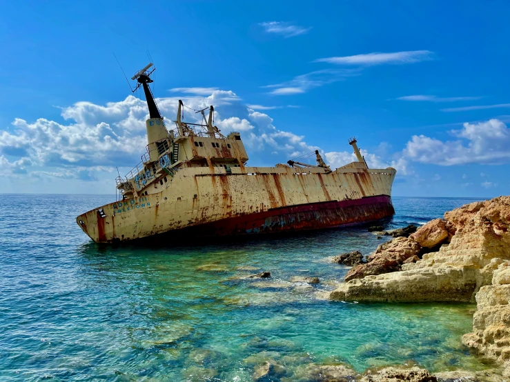 a ship laying upside down in the water near rocks