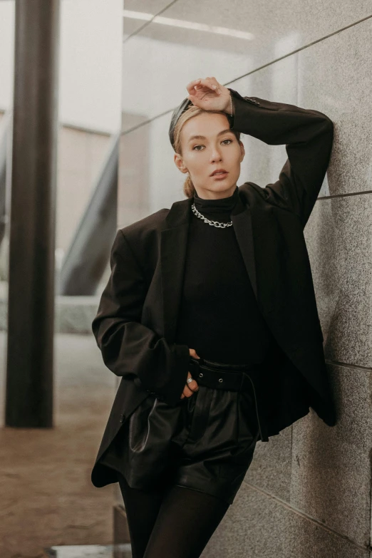 woman wearing black standing against a wall leaning on a wall