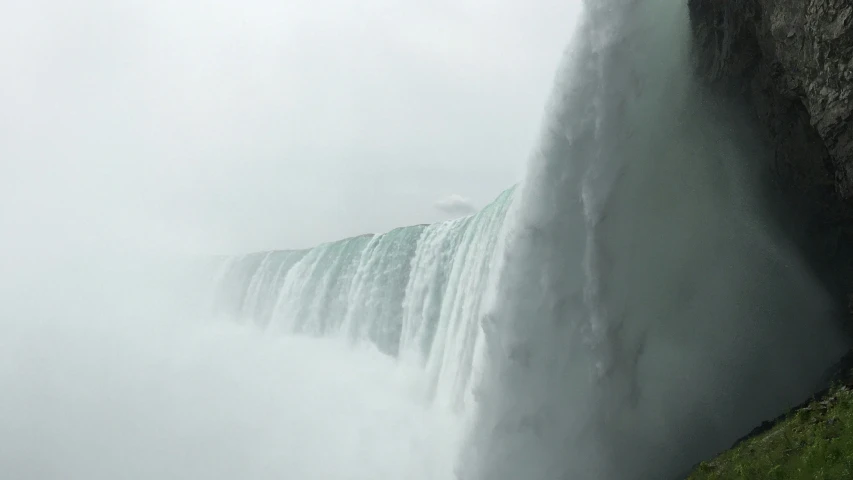 the top of a tall waterfall with a large water fall in the background