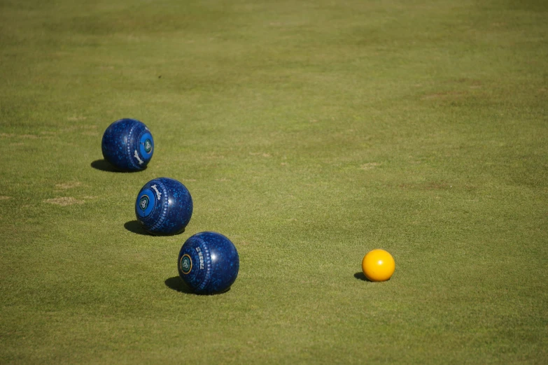 three ball shapes sitting on a field near two large balls