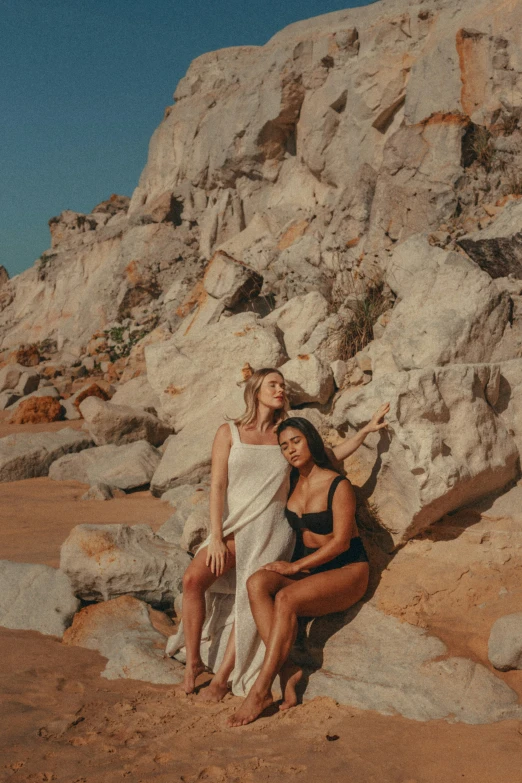 two woman sitting on the beach under towels