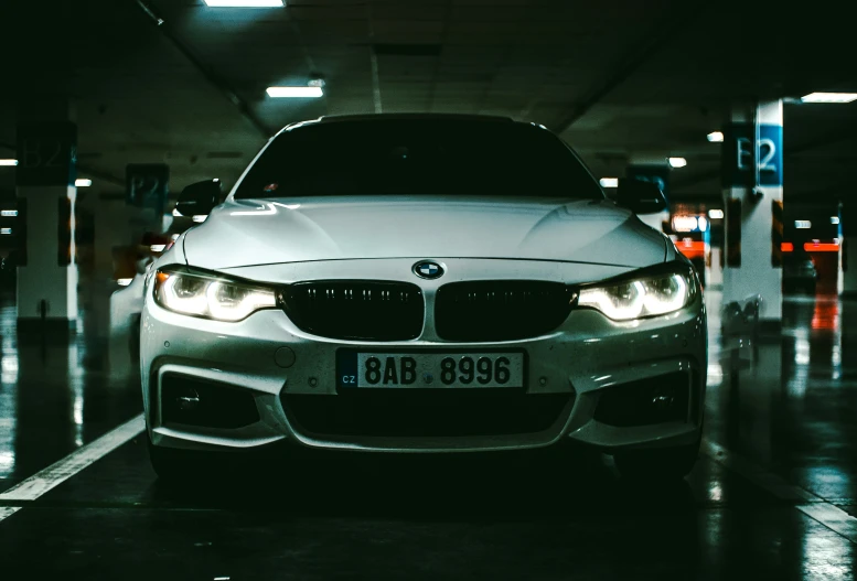 a white bmw car sitting in front of an open air parking space