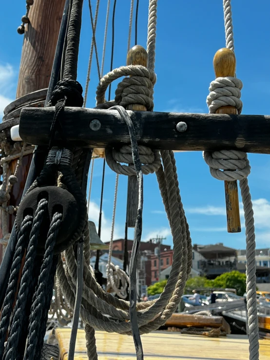 the ropes of a sailboat and a ship in the background