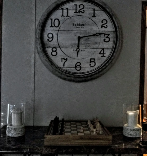 a clock mounted on the wall above a book shelf