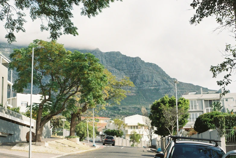 a small car parked in the street and mountains behind it