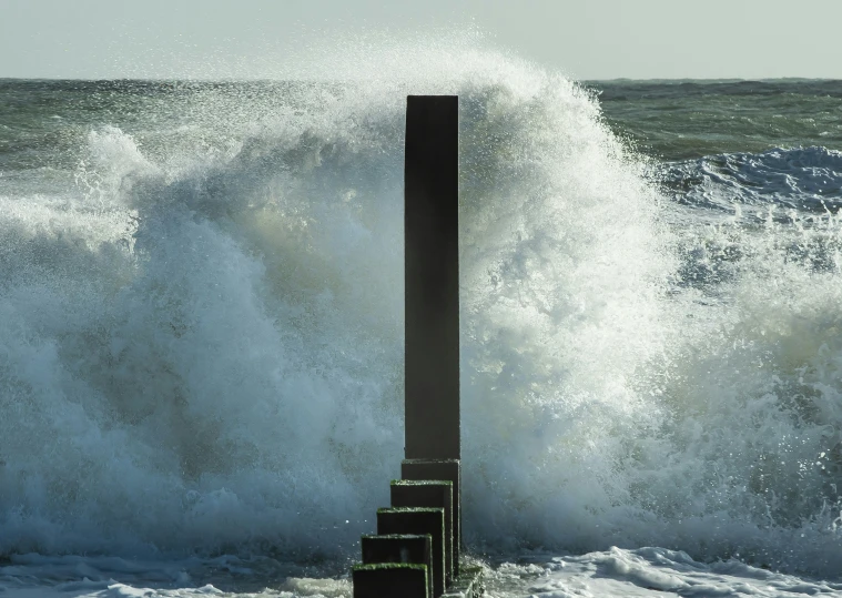 a pole is standing in the middle of the ocean with waves crashing against it