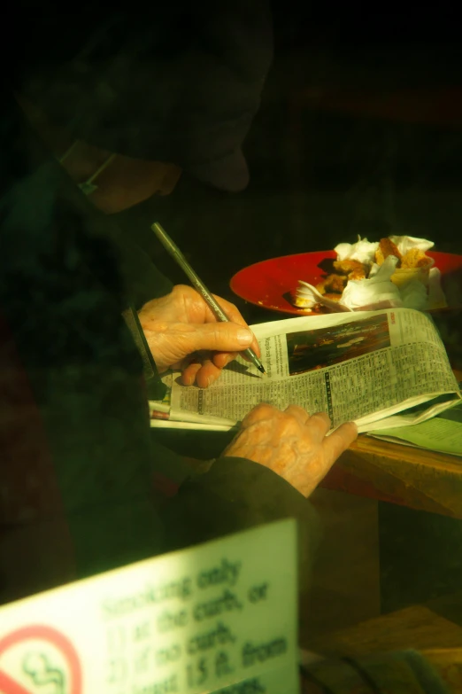 a person reads an article on their cell phone while holding a menu and sitting at a table