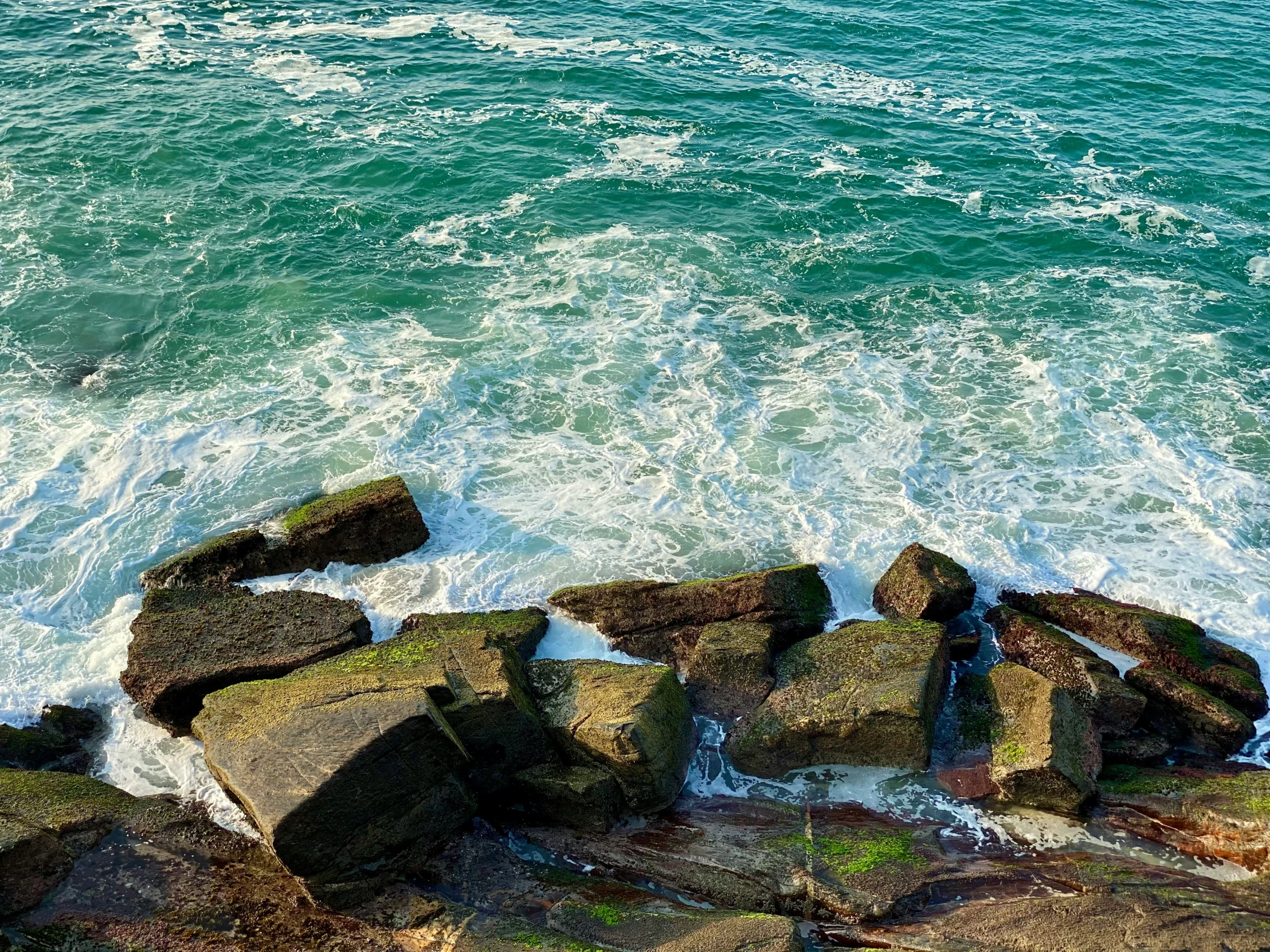 an ocean view with rocks and waves