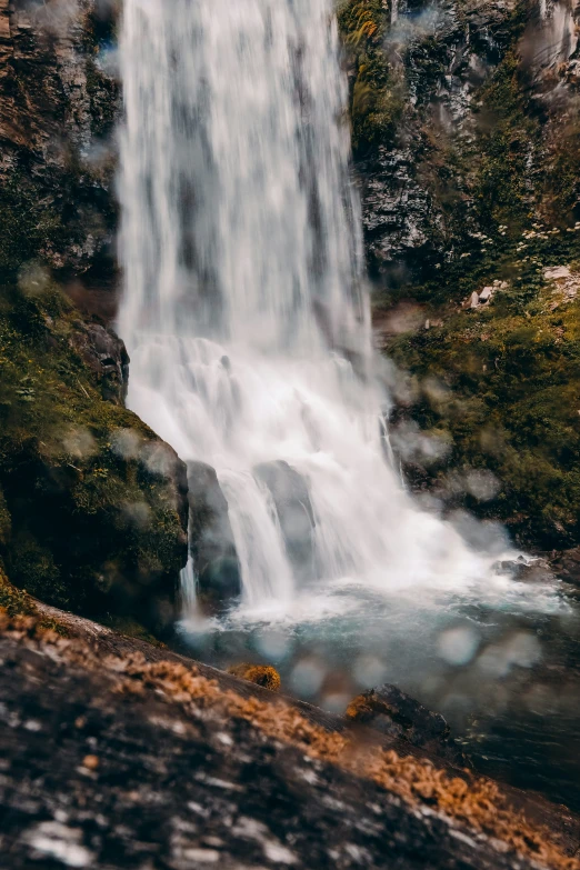 a small waterfall with rain drops at top