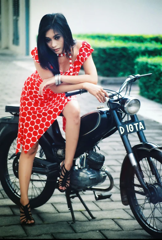 a woman sitting on a motorcycle in front of some bushes