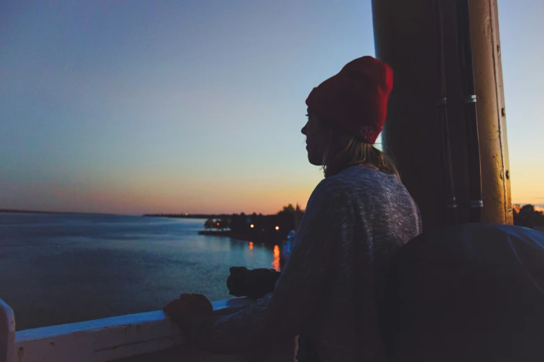 a woman looking out over the water at sunset