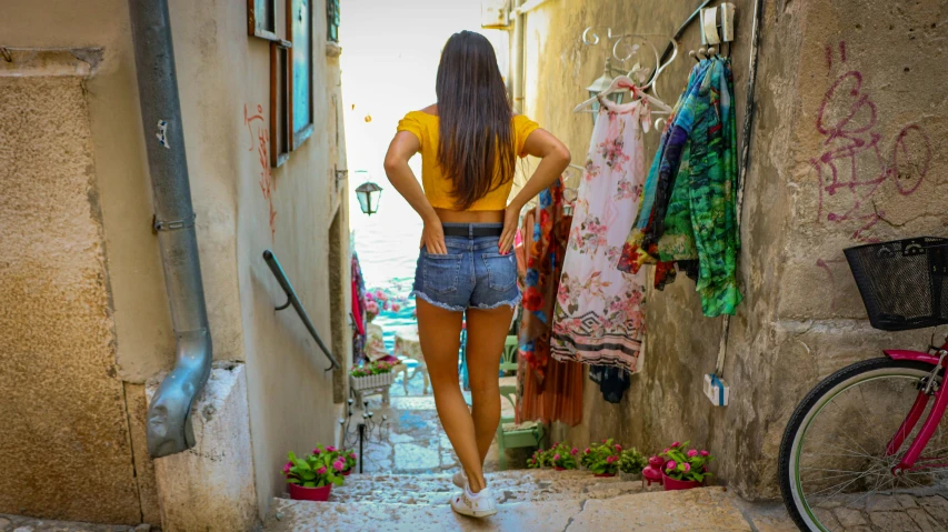 a woman in yellow shirt looking at the street and some clothes