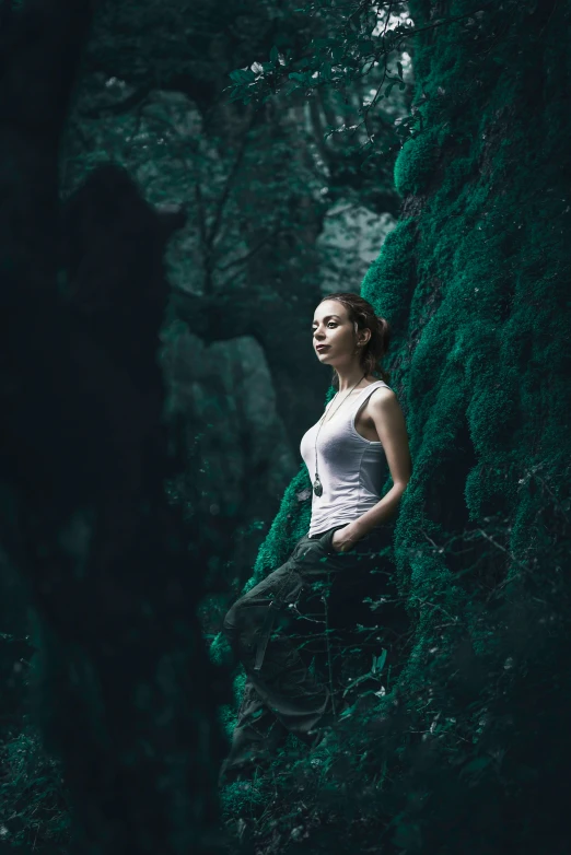 a woman standing on a cliff wearing a white shirt