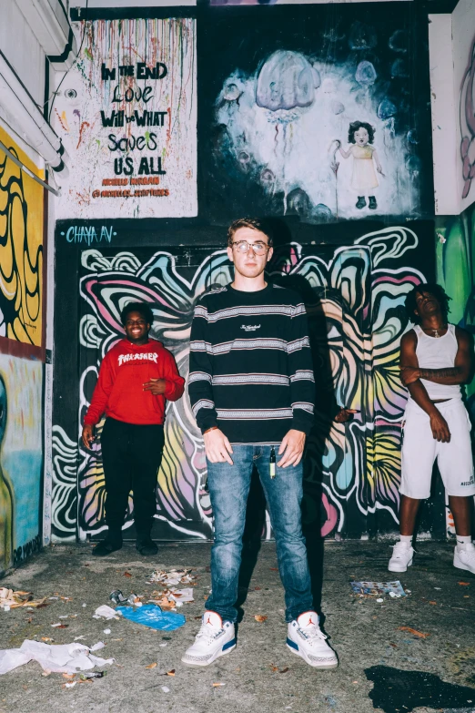 a man wearing glasses standing in front of colorful walls with graffiti