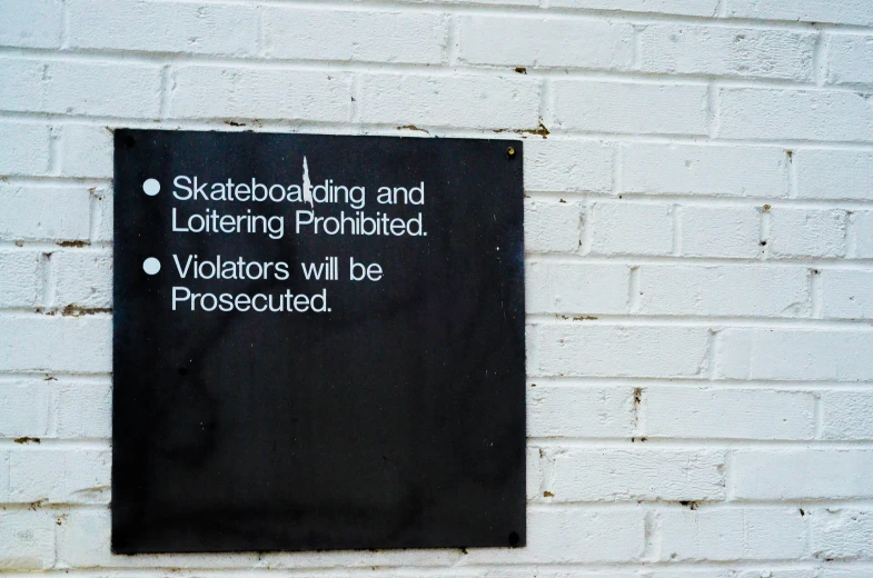 a sign on a wall that warns that skateboarding and listening prohibited