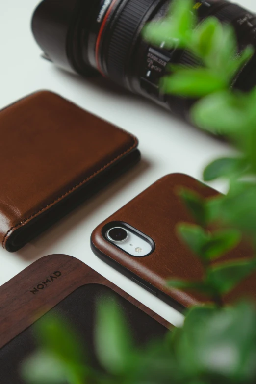 a leather wallet is next to a camera, and a pair of cellphones