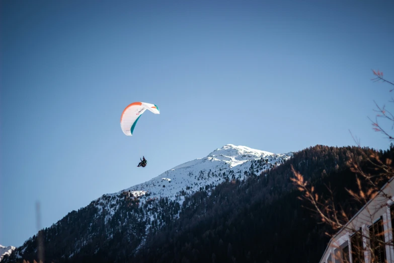 two parachutes soaring above a mountain with snow on top