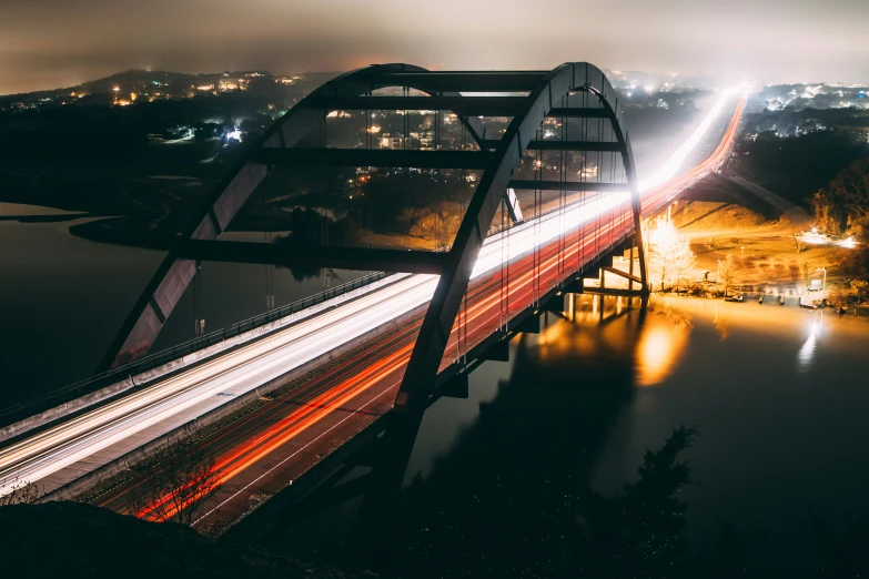 a large long bridge spans over water with bright lights shining in the background