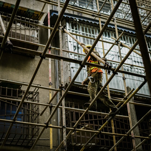 workers in a steel ladder are fixing scaffolding near a tall building
