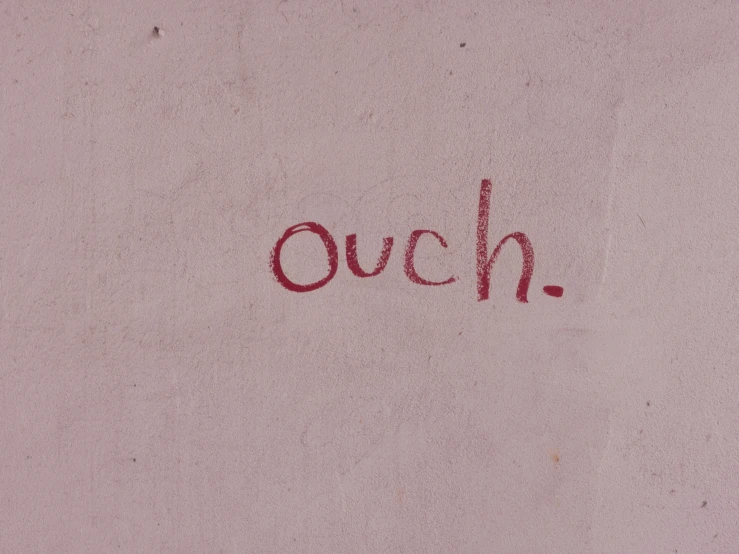 an over - sized picture with the word ouch written in red ink on a pink surface