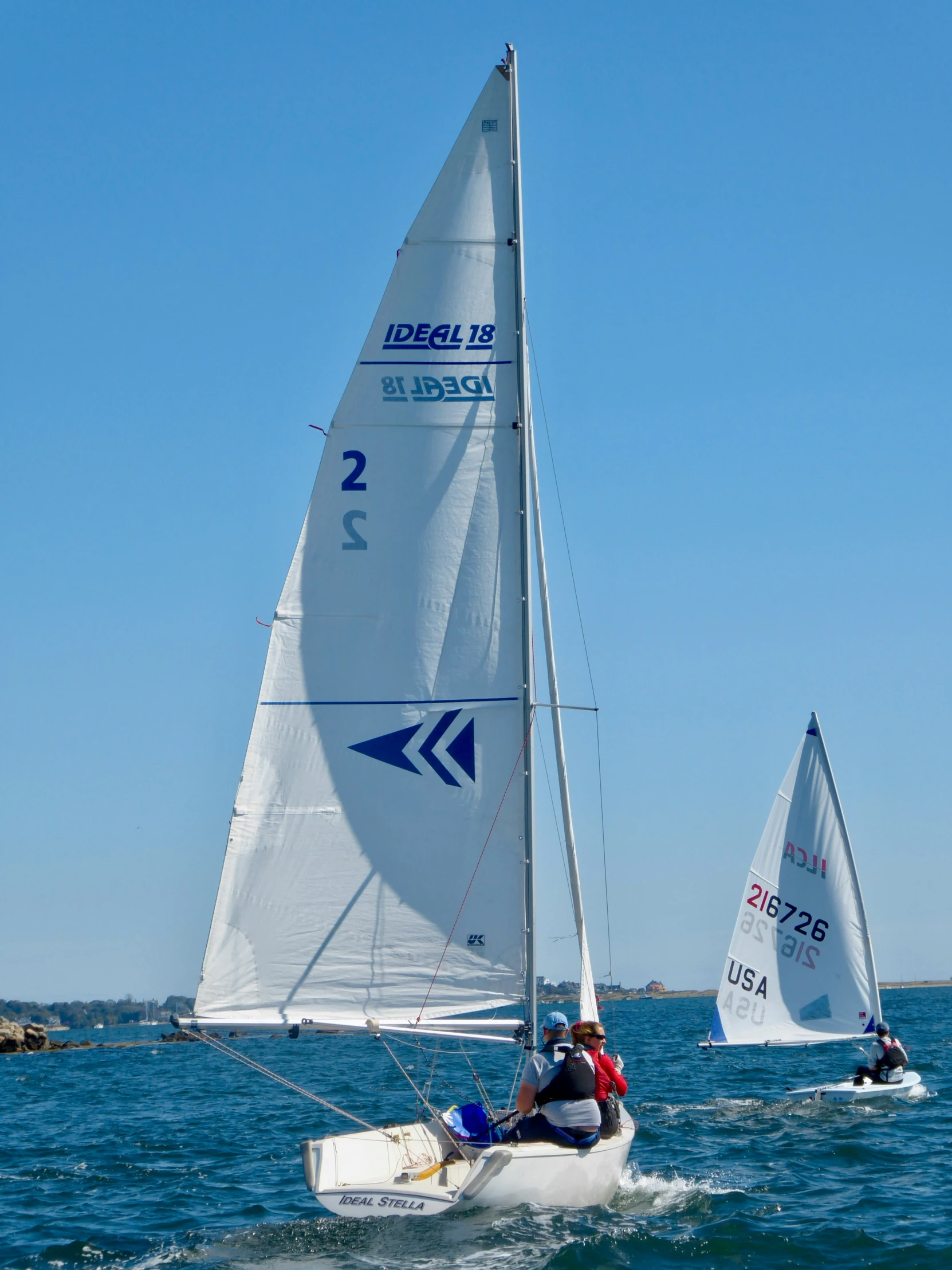 people on small sailboats on the water with sails down