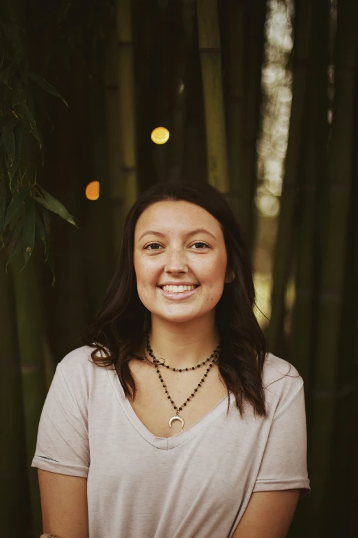 a woman smiles at the camera with bamboo behind her