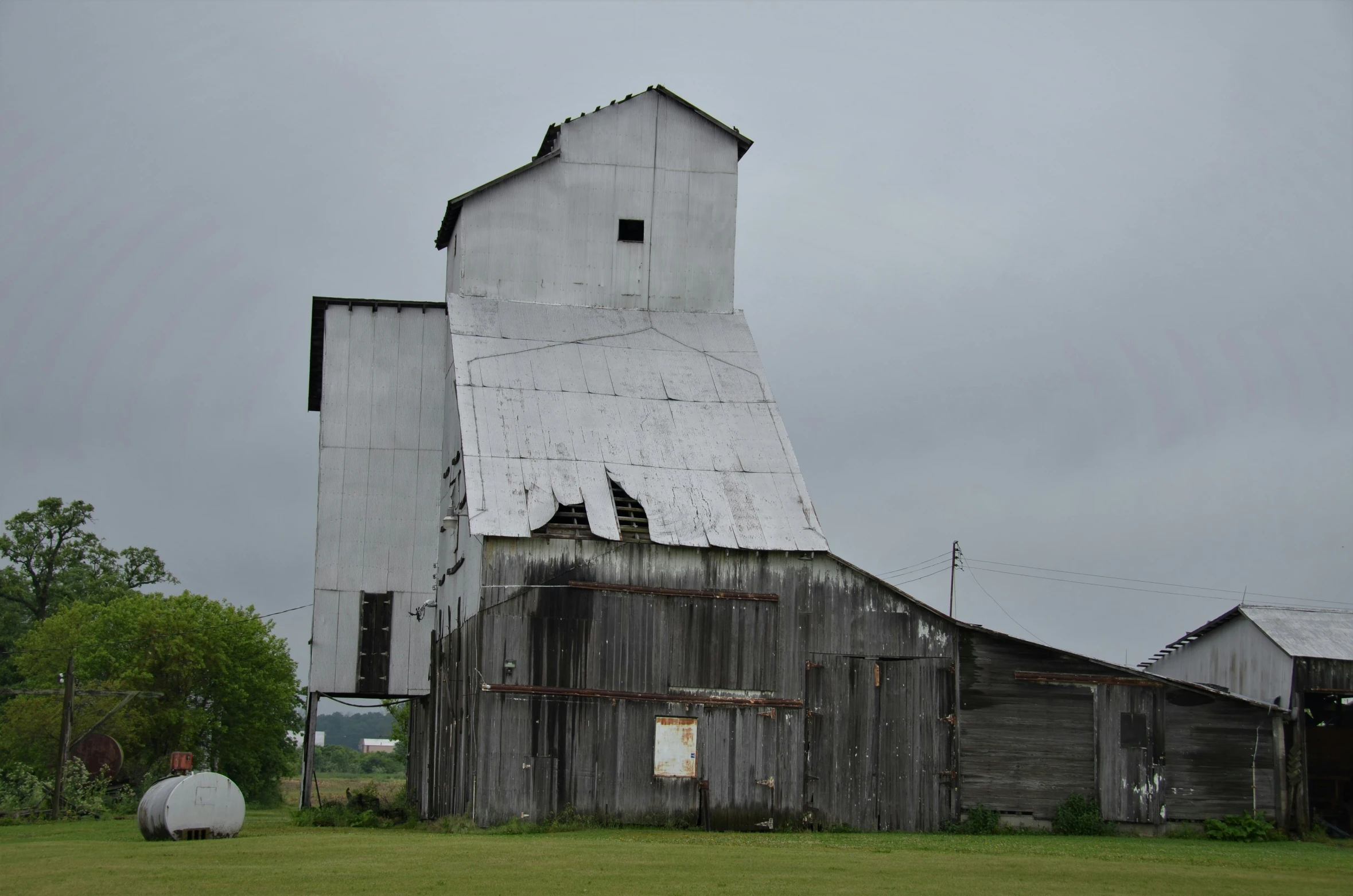 an old barn that's in a field with a big silo