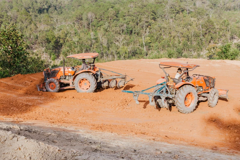 two men drive tractors on a farm during the day