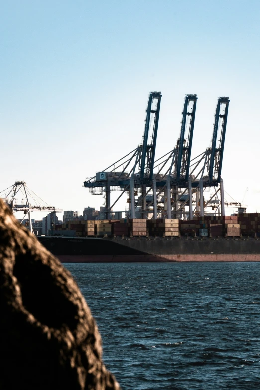 a large ship sailing past tall cranes