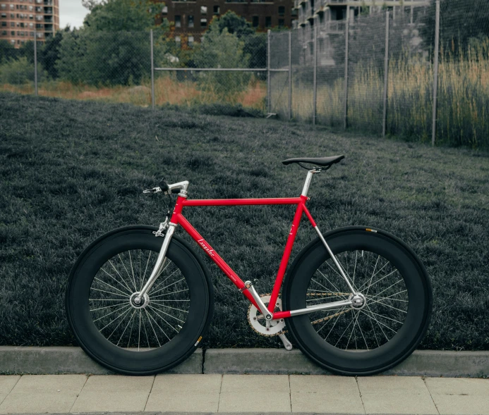 red bike leaning against black iron bar in urban area