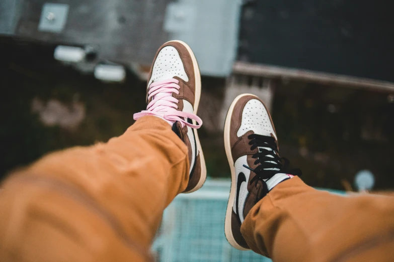 a person's feet wearing brown shoes with a pink cord