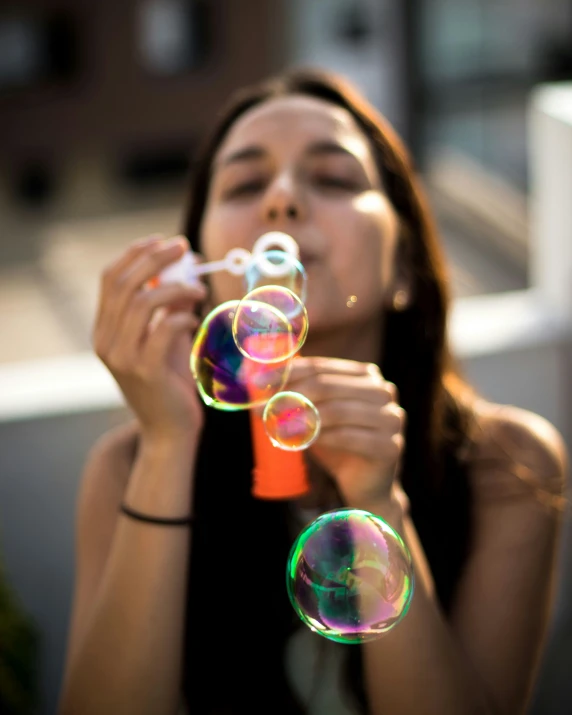 a young woman blows bubbles off her face