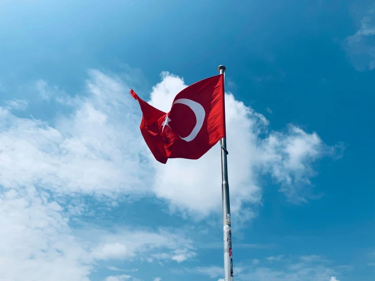 a flag flying with a cloudy blue sky in the background