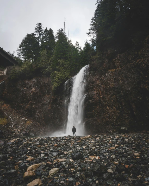 the man is standing in front of a waterfall