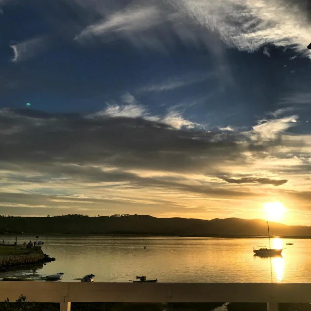 a couple of boats floating on a body of water at sunset