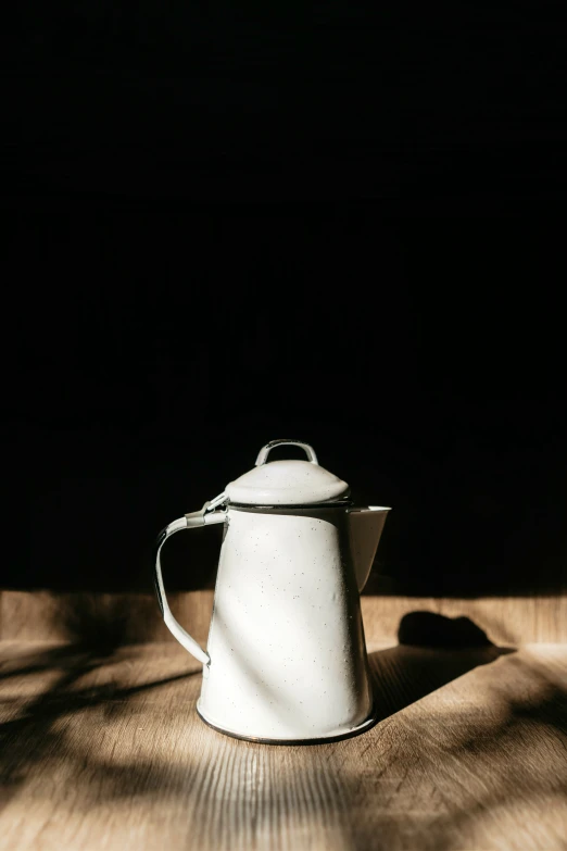 a white teapot sitting on top of a wooden floor