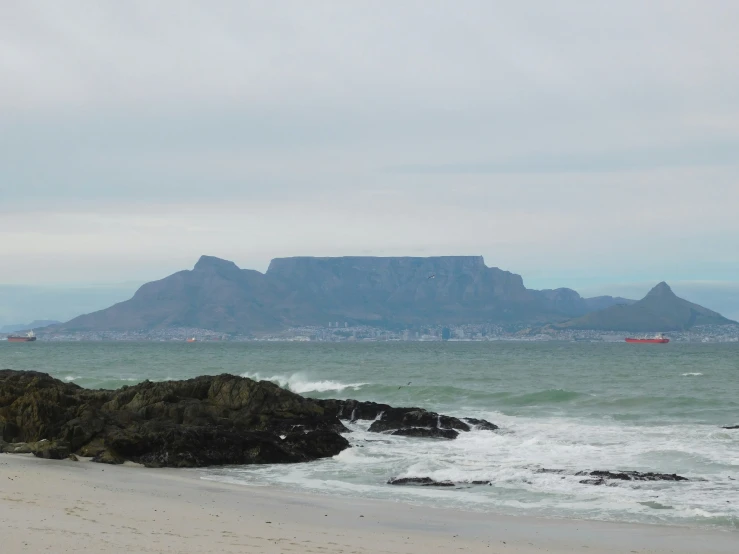 a man sitting at the edge of the water looking out to the ocean