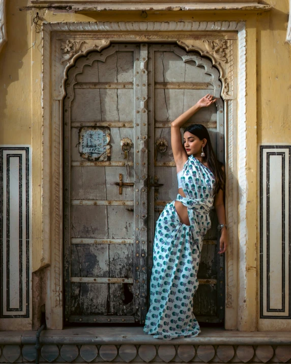 a woman in a white dress posing by a door