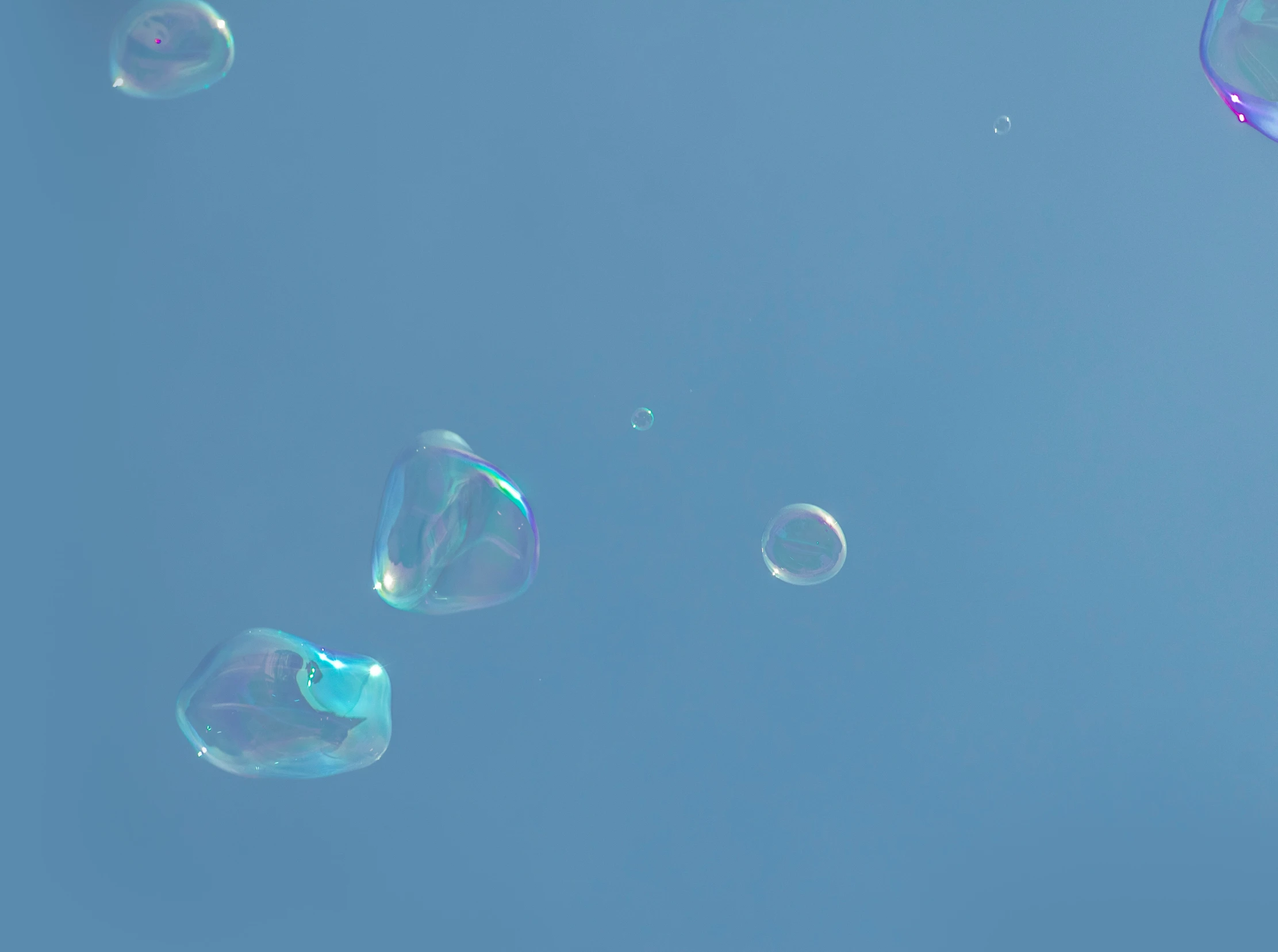 three soap bubbles floating in the air against a blue sky