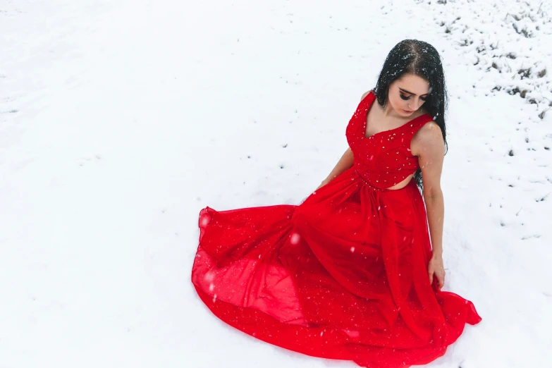 a woman in a red dress sitting on a snowy hill