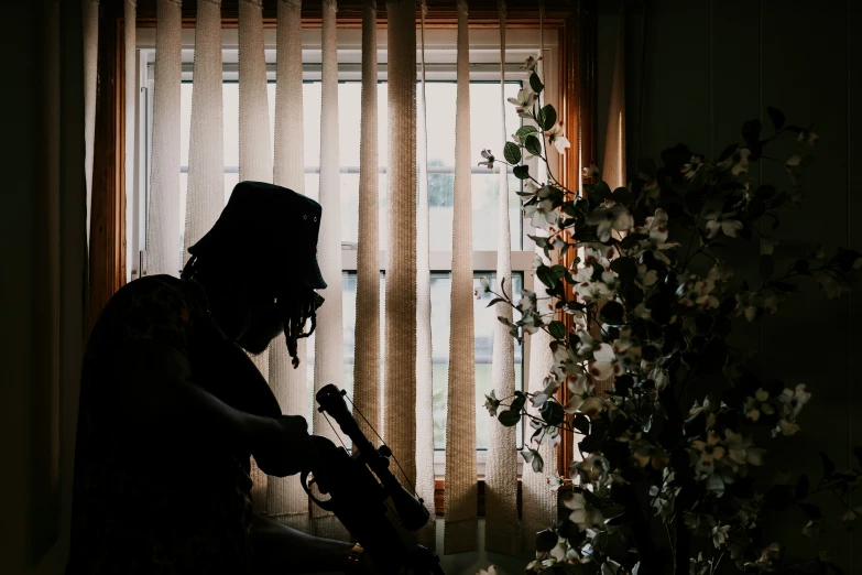 silhouette of person standing by window holding guitar